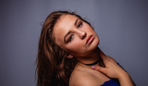 Portrait of young woman against gray background