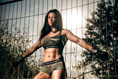 Beautiful young woman wearing hat against fence