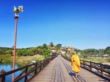 Rear view of a monk walking on footbridge