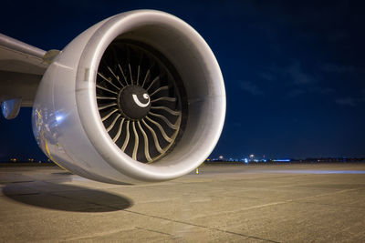 Close-up of jet engine on runway against blue sky