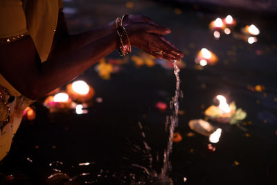 Close-up midsection of woman pouring water in river