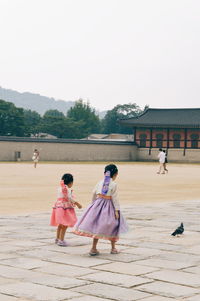 People walking by building against sky