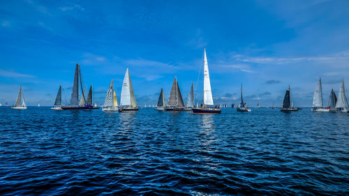 Sailboats sailing in sea against blue sky