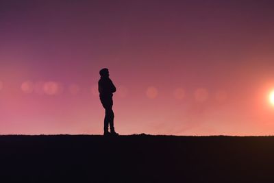Silhouette woman standing on field against sky during sunset