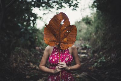 Woman holding dry leaf while standing on field