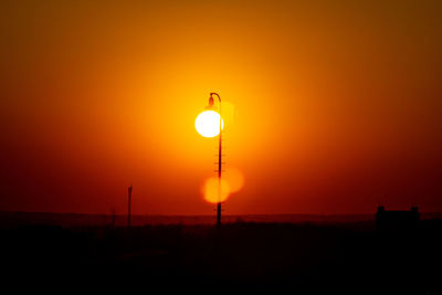 Silhouette street light against orange sky during sunset