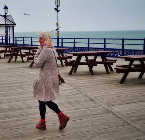 Woman walking on pier against sky