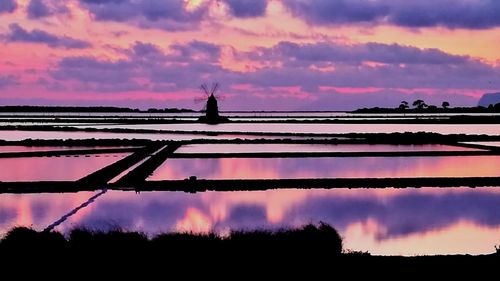 Silhouette cranes against sky during sunset