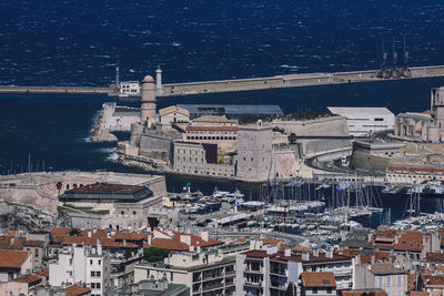 High angle view of cityscape by sea against blue sky