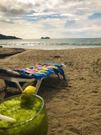 Lounge chairs on beach against sky