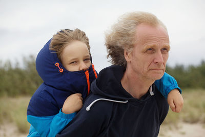 Mature man giving piggy back ride to grandson