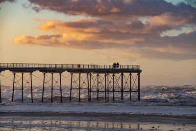 Pier over sea against sky during sunset