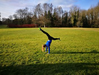 Full length of woman doing handstand on field against trees