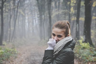 Side view portrait of woman standing in forest during foggy weather