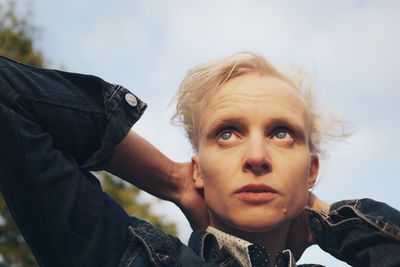 Mid adult woman with hands behind head against sky