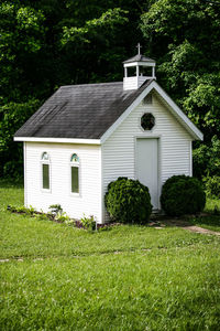 House on field against trees and building