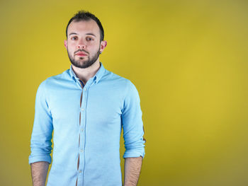 Portrait of young man standing against yellow background