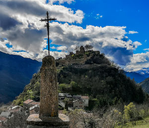 Cross against trees and buildings against sky