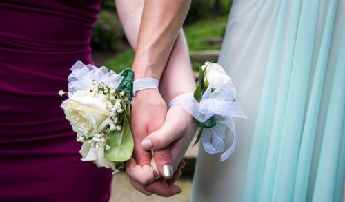 Midsection of couple holding bouquet