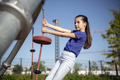 Low angle view of girl playing on jungle gym 