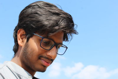 Close-up of young man wearing eyeglasses against sky