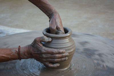 Hands working on pottery wheel and making a pot