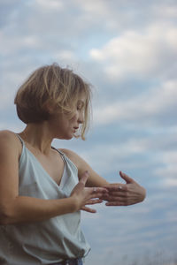 Woman with arms raised standing against sky