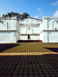 Rear view of woman walking in building against sky