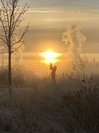 Silhouette man on field against sky during sunset