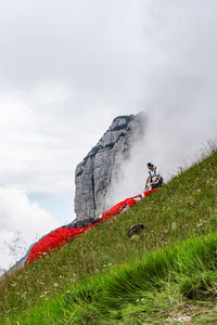 People on field by mountain against sky