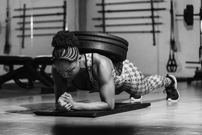 Woman training in modern light studio. doing a plank with weight on your back. flexion on weights.