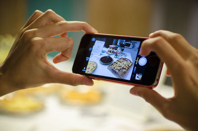 Cropped hands photographing food on table