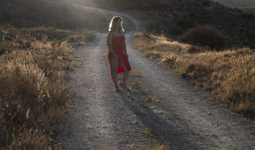 Woman in red dress walking on footpath of field in summer