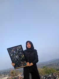 Full length of young woman standing against clear sky