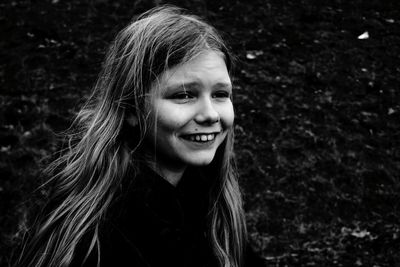 Smiling girl looking away while standing against plants