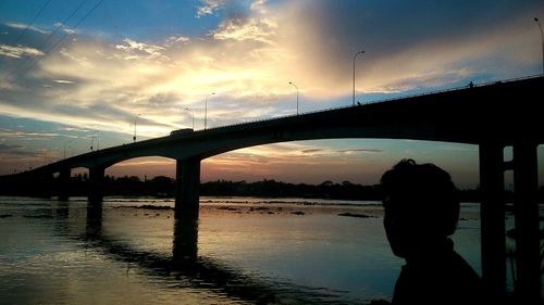 Silhouette bridge over river against sky during sunset