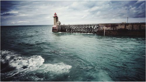 Lighthouse by sea against sky