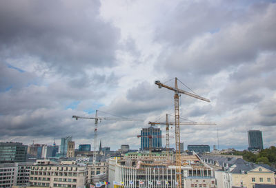 Cranes in city against sky