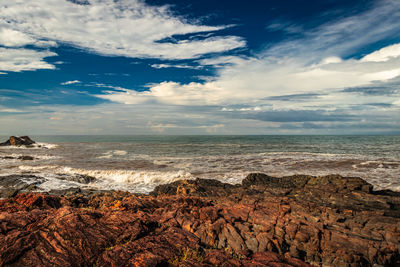 Rocky sea beach with crashing waves at morning from flat angle