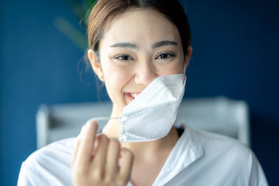 Portrait of smiling young woman wearing surgical mask