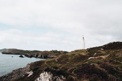 Lighthouse by sea against sky