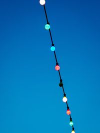 Low angle view of lighting equipment against clear blue sky