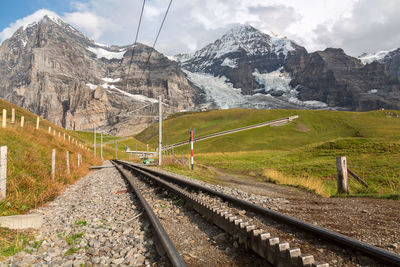 Railroad track by mountains against sky