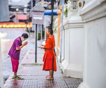 Rear view of people walking on street amidst buildings