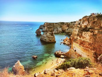 Rock formations by sea against clear sky