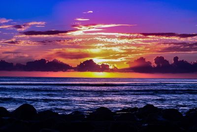 Scenic view of sea against dramatic sky during sunset