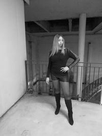 Portrait of young woman standing against wall