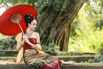 Young woman in traditional clothing holding paper umbrella