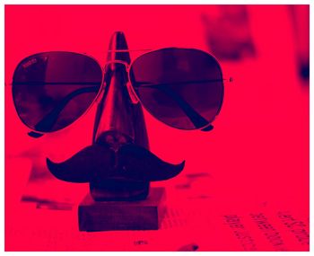 Close-up of sunglasses on table against red background