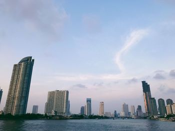 Sea by modern buildings against sky in city